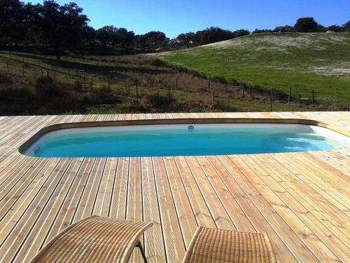 a swimming pool with a chair and a wooden deck at Taipa 2 - Casas de Campo do Junqueirinho in Bicos