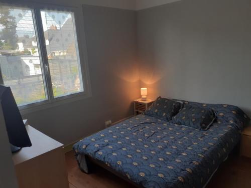 a bedroom with a bed with a blue comforter and two windows at Loue chambre chez l habitant 24h du Mans voiture in Le Mans