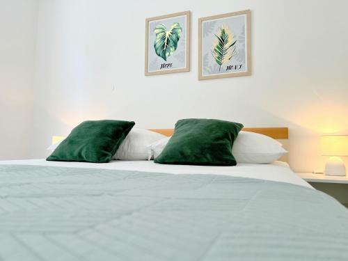 a white bed with two green pillows on it at Rab City Apartment Greeny in Rab