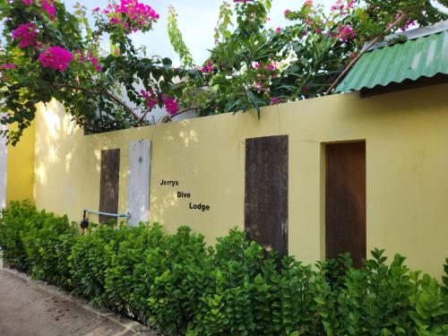a building with flowers on the side of it at Jerrys Dive Lodge Rasdhoo in Rasdu