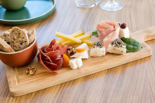 una tabla de cortar de madera con diferentes tipos de comida. en Domaine Les Sources de Dieulefit, en Dieulefit