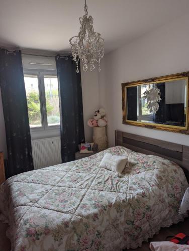 a bedroom with a large bed and a chandelier at Chez Nonna in Jonage