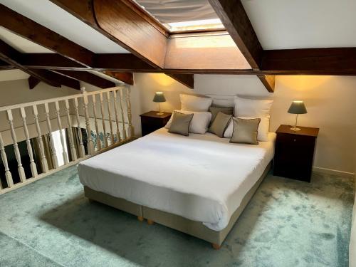a bedroom with a large white bed with a skylight at Hotel Le Cardinal Rueil Centre in Rueil-Malmaison