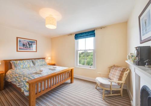 a bedroom with a bed and a window and a chair at Oystershell Cottage in Kingswear