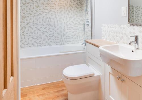 łazienka z toaletą, umywalką i wanną w obiekcie Oystershell Cottage w mieście Kingswear