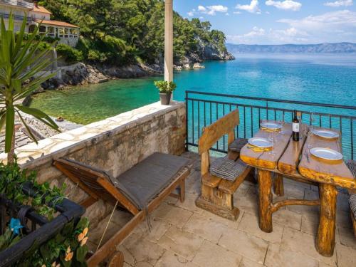 una mesa de madera y sillas en un patio con vistas al océano en Apartments Vela Stiniva en Zastražišće