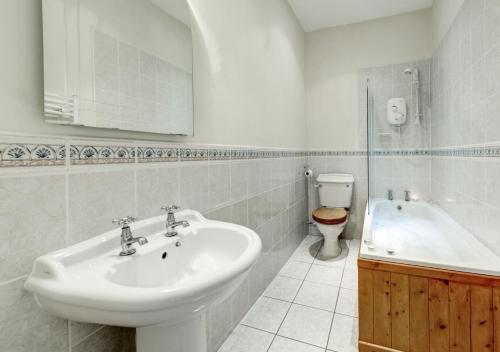uma casa de banho com um lavatório, uma banheira e um WC. em Buckland House em Slapton