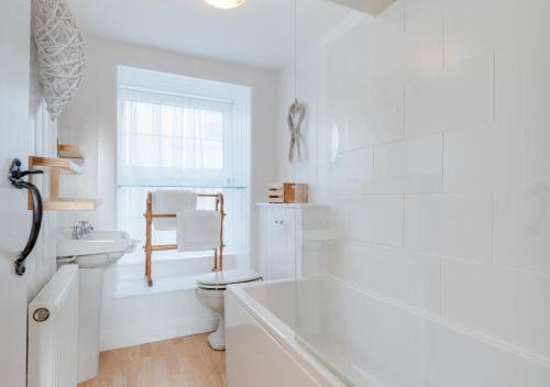 a white bathroom with a tub and a toilet at Jasmine Cottage in Brixham