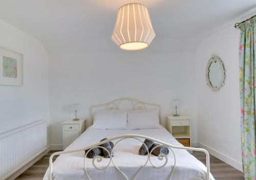 a white bedroom with a bed and a light fixture at Saltrock Cottage in Kingsbridge