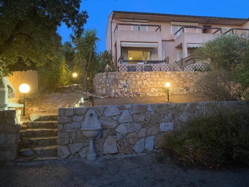 un mur en pierre devant une maison la nuit dans l'établissement Calvi Lumio location face mer, à Lumio