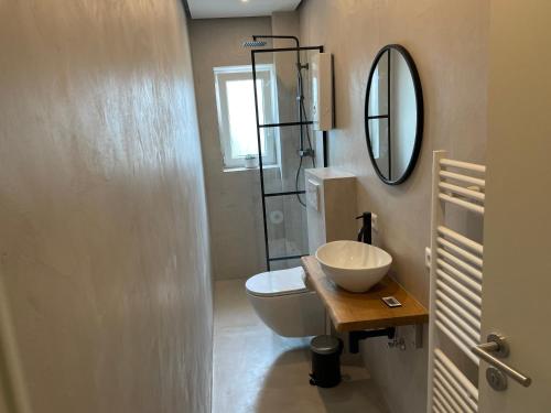 uma casa de banho com um WC, um lavatório e um espelho. em Neue stilvolle 2-Zimmer Wohnung im Zentrum von Wolfsburg em Wolfsburg