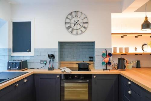 a kitchen with black cabinets and a clock on the wall at Luxury holiday home in central Truro in Truro