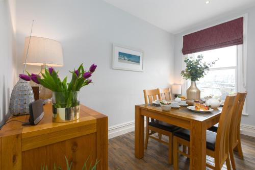 a living room with a dining room table with a vase of flowers at Arghanti in St Ives