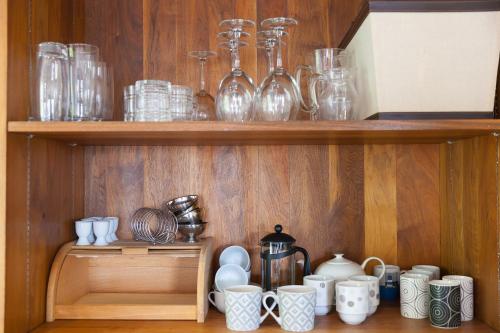 a wooden shelf with glasses and cups and mugs at Arghanti in St Ives