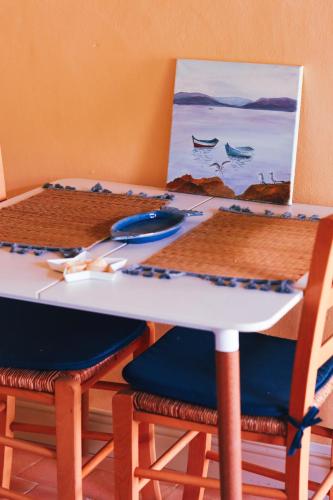 une table avec deux chaises et un tableau de bateaux dans l'établissement TY La Source, à Plestin-les-Grèves