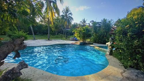 a swimming pool in a yard with palm trees at Matahari Inn Kuta Lombok in Kuta Lombok