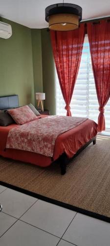 a bedroom with a bed with red curtains and a window at Chambre Gaëlle et Brian in Cardet