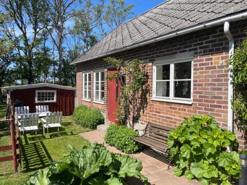 una casa de ladrillo con una puerta roja y un banco en Lyckås Gårds Gästboende, en Höganäs