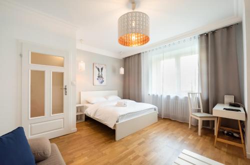 a bedroom with a bed and a desk and a window at Ogrodowa White Apartment in Warsaw