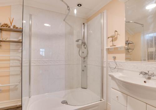 a white bathroom with a shower and a sink at Bayards Cottage in Dartmouth