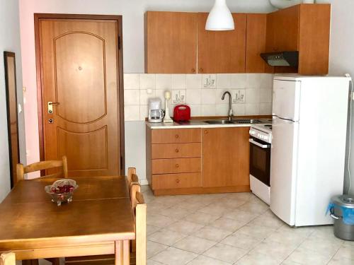 a kitchen with a table and a white refrigerator at Mina Apartments 4 Nea Kallikrateia in Nea Kalikratia