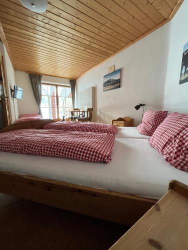 Cama grande con mantas y almohadas rojas y blancas en Landhaus Alpenstern, 