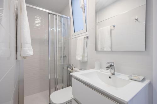 La salle de bains blanche est pourvue d'un lavabo et d'une douche. dans l'établissement Sea Views Private Terrace 2BR House near the Beach, à Telde