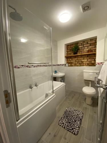 a bathroom with a tub and a toilet and a sink at Spacious 4 Bedroom House in Northampton by HP Accommodation - Free Private Parking in Northampton