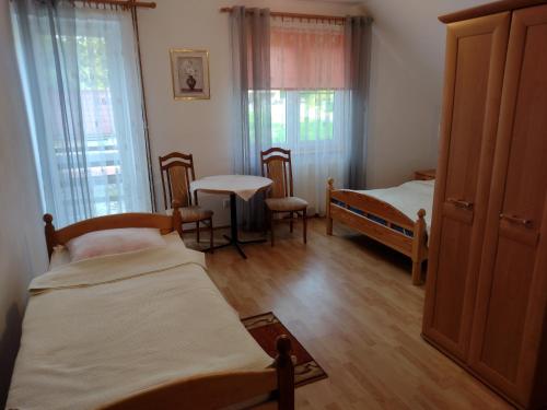 a room with two beds and a table and windows at Zajazd nad stawami in Uherce Mineralne (7)