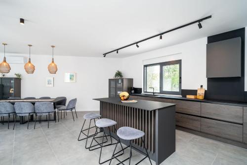 a kitchen with a counter and a table with stools at Villa Luce in Čilipi