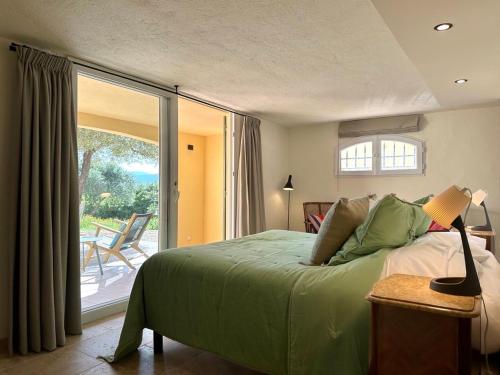 1 dormitorio con cama verde y balcón en Villa Leopard Grimaud, en Grimaud