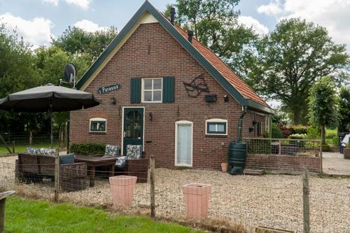 a small brick house with an umbrella in front of it at Pothuus 2 persoons vrijstaand huis met vrij uitzicht in de Achterhoek in Ruurlo