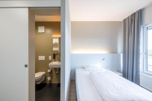 a hotel room with a bed and a bathroom at mk hotel stuttgart in Stuttgart