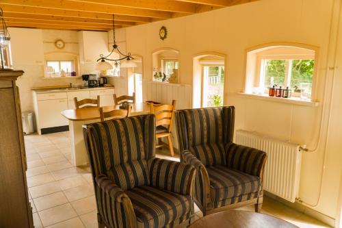 a living room with two chairs and a kitchen at Pothuus 2 persoons vrijstaand huis met vrij uitzicht in de Achterhoek in Ruurlo