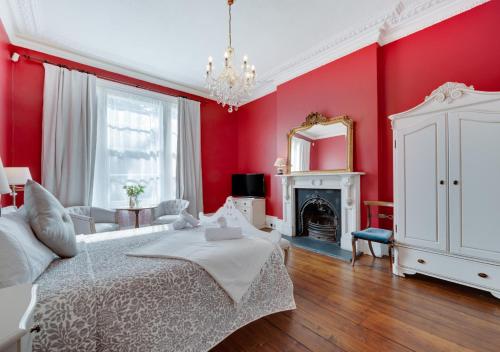 a red bedroom with a white bed and a fireplace at Vane Hill Crest in Torquay