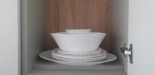 a stack of plates and bowls on a shelf in a cabinet at VIEW APARTMENT in Visoko