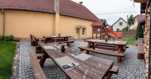 a patio with wooden tables and benches in a yard at Penzion U Kapličky in Malá Hraštice