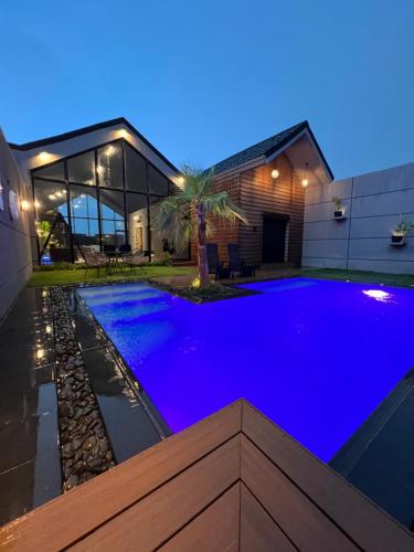 a swimming pool in front of a house with blue lighting at شاليه كوتج in Buraydah