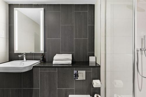 a bathroom with a sink and a mirror and a shower at Mercure Paignton Hotel in Paignton