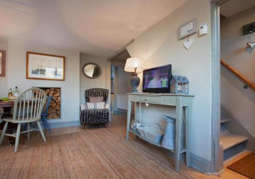 a living room with a table with a tv on it at Compass Cottage Shaldon in Shaldon