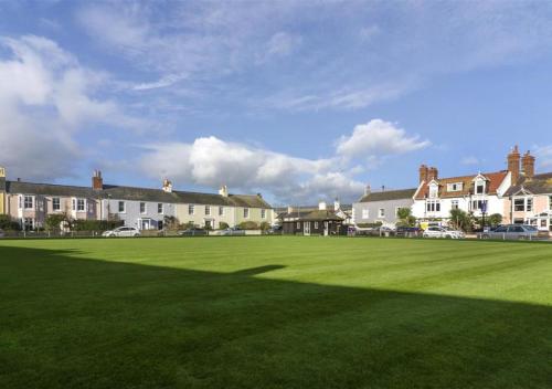 a large green field with houses in the background at Compass Cottage Shaldon in Shaldon