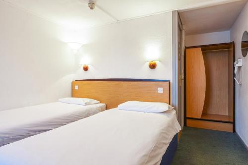 ウェイクフィールドにあるカンパニール ホテル ウェイクフィールドの白い壁の小さな部屋のベッド2台