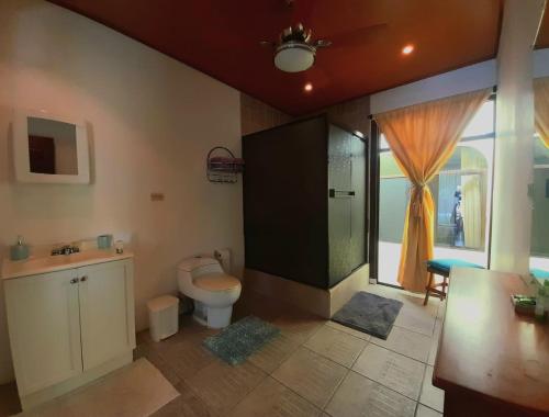 a bathroom with a toilet and a shower with a window at Nirvana Apartament Hostal in Alajuela
