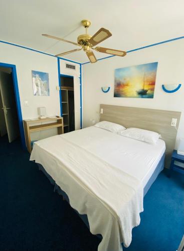 a bedroom with a white bed with a ceiling fan at Hotel Cyrnea in Bastia