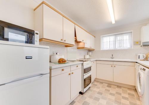 a kitchen with white appliances and white cabinets at Abbey Mews in Torquay