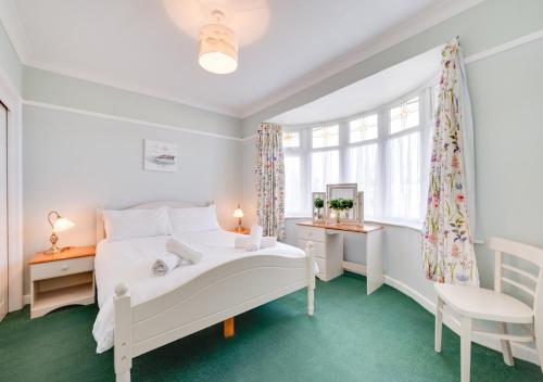 a white bedroom with a white bed and a window at Preston Down in Paignton