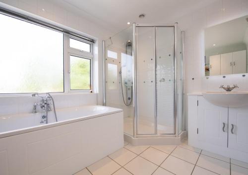 a bathroom with a tub and a sink and a shower at The Firs in Churston Ferrers
