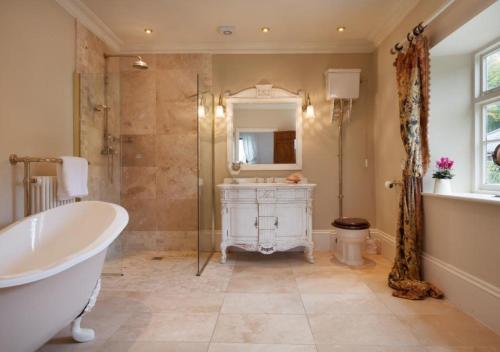 a bathroom with a tub and a sink and a mirror at Hutchinghayes Farmhouse in Honiton