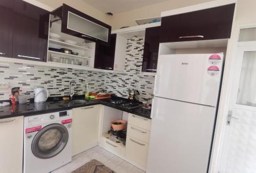 eine Küche mit einem weißen Kühlschrank und einer Waschmaschine in der Unterkunft Adventurous Local Hostel in Fethiye