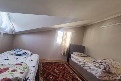 a small bedroom with two beds and a window at Sunshine Guest house with terrace in Fethiye
